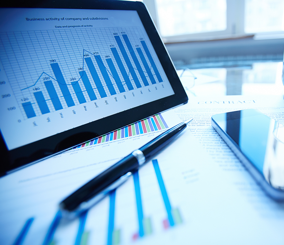 Image of documents, pen, cellular phone, glass of water and touchpad on workplace - graphs and charts representing analytics