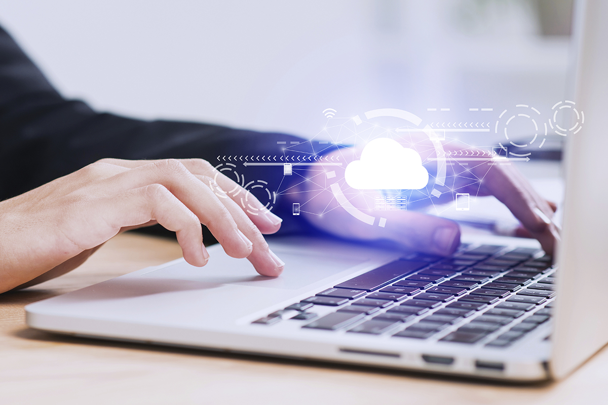 Person working on a laptop with a cloud icon overlayed on the image - cloud solutions