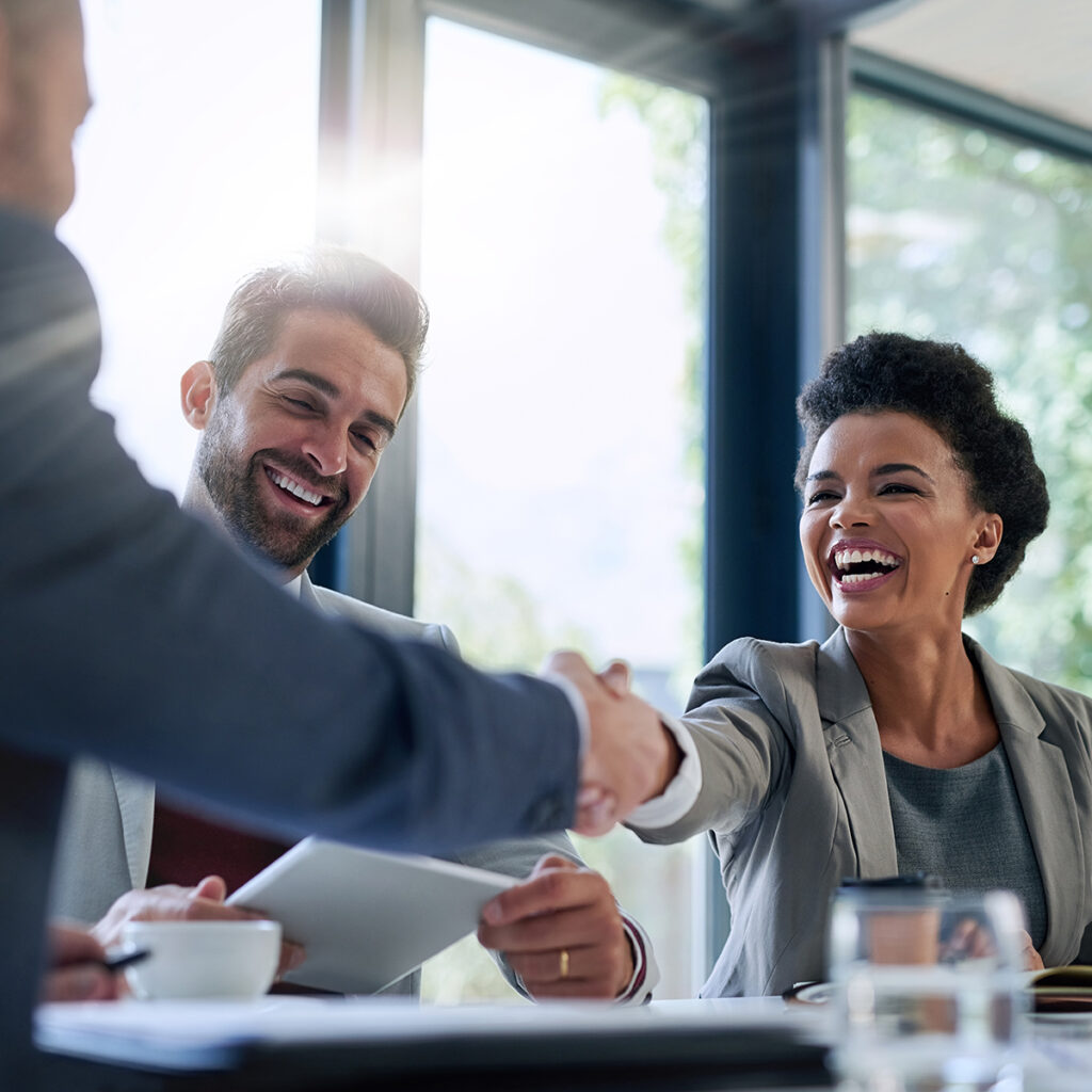 Meeting, partnership and business people shaking hands in the office for a deal, collaboration or onboarding. Diversity, professional and employees with handshake for agreement, welcome or greeting.